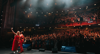At B Corp festival, two host wearing red are taking a selfie with a full stadium of audience.